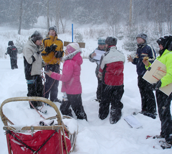 Mushers, officials, and "dogs" all enjoy a sticky bun snack at the "Braeburn" checkpoint in a Yukon Quest simulation at a school.